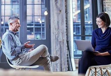 A man and a woman seated across from each other engaged in conversation